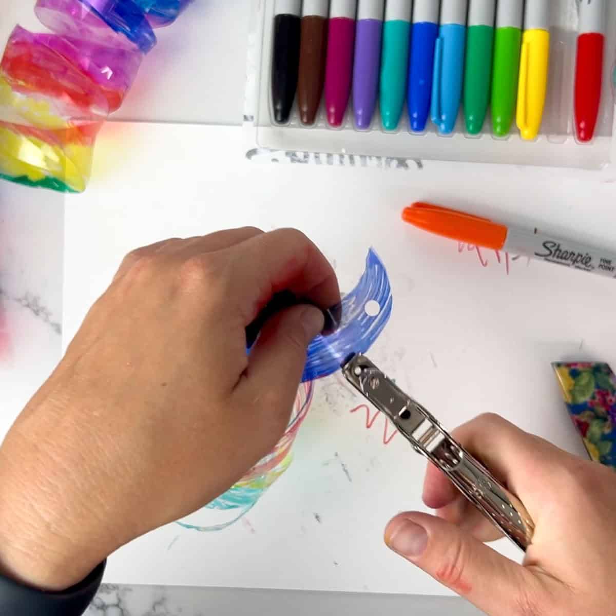 hands using a hole punch on plastic spiral.