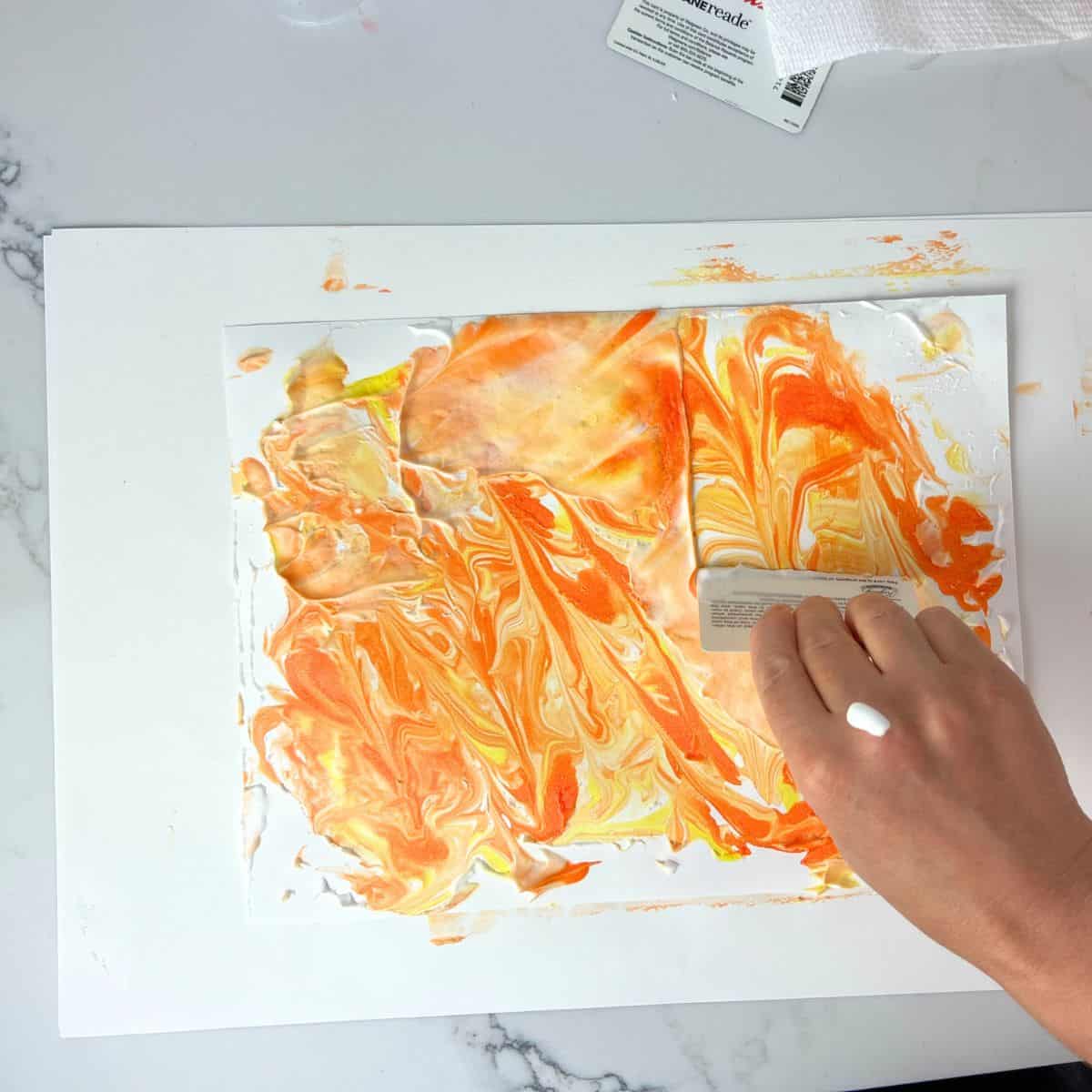 hand scraping off paint and shaving cream off paper.