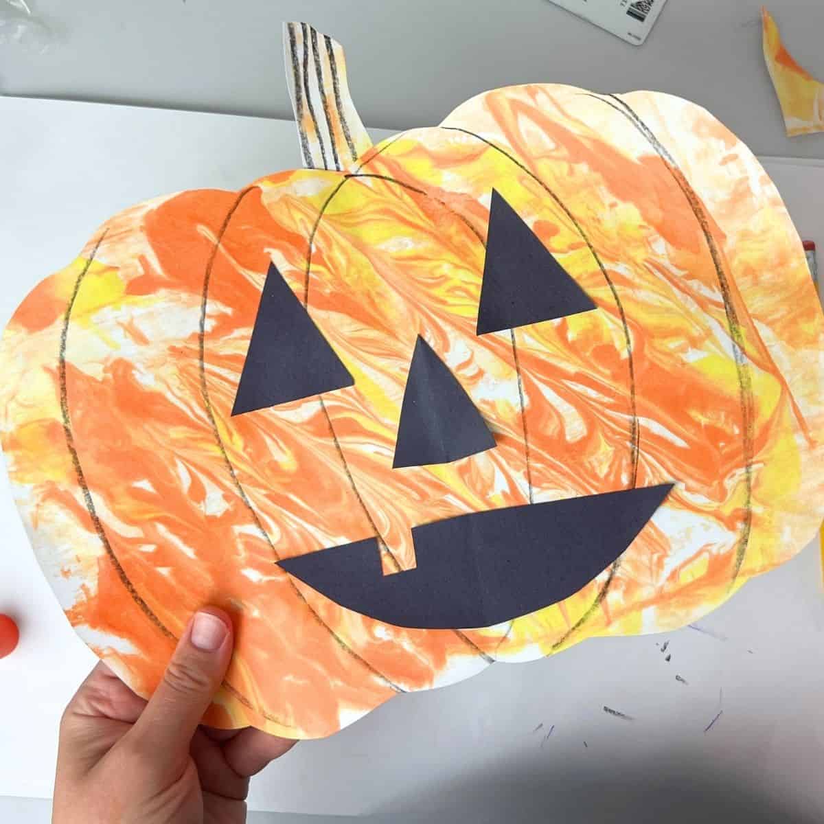 hand holding shaving cream pumpkin kid art project.