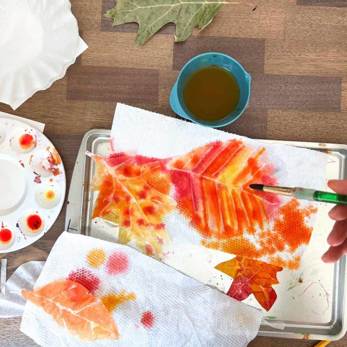 paint brush adding watercolor paint to coffee filter leaf shape.