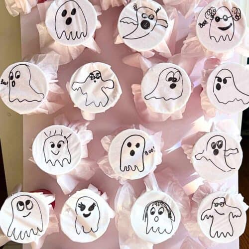 ghosts drawn on white tissue paper wrapped around cups.