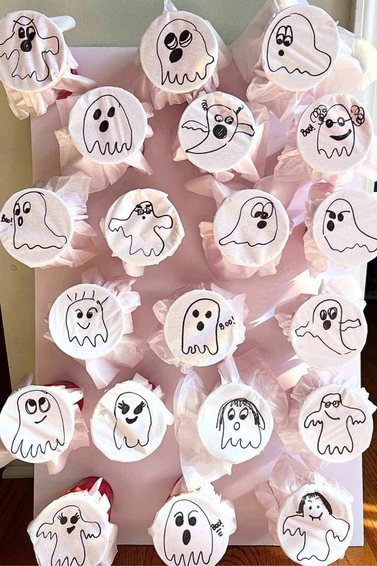 ghosts drawn on white tissue paper wrapped around cups.