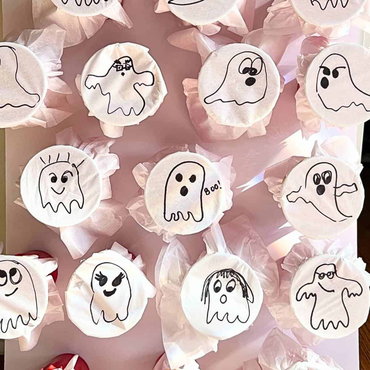 DIY poke a ghost game with ghosts drawn on white tissue paper wrapped around cups.