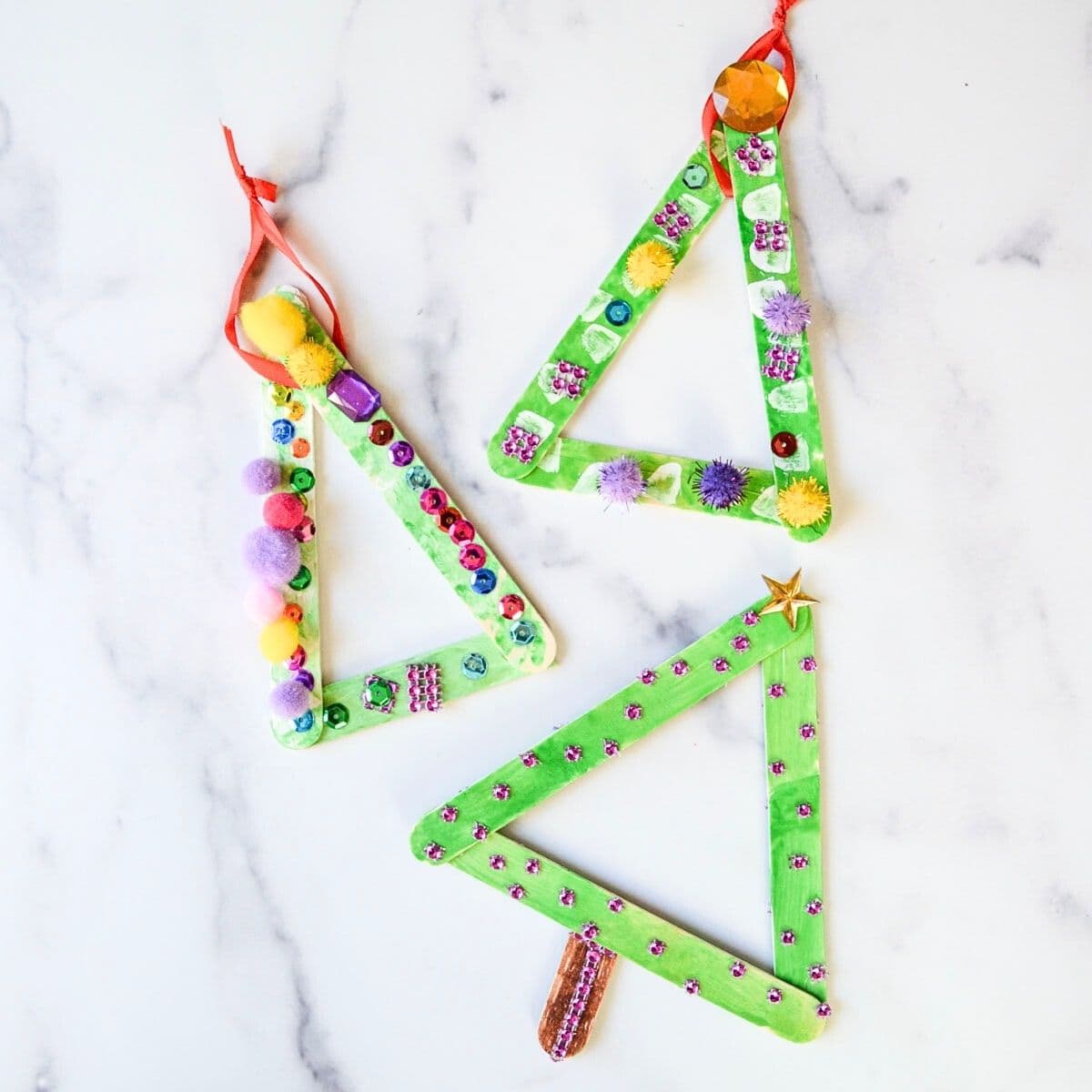 3 popsicle stick Christmas tree ornaments with decorations.