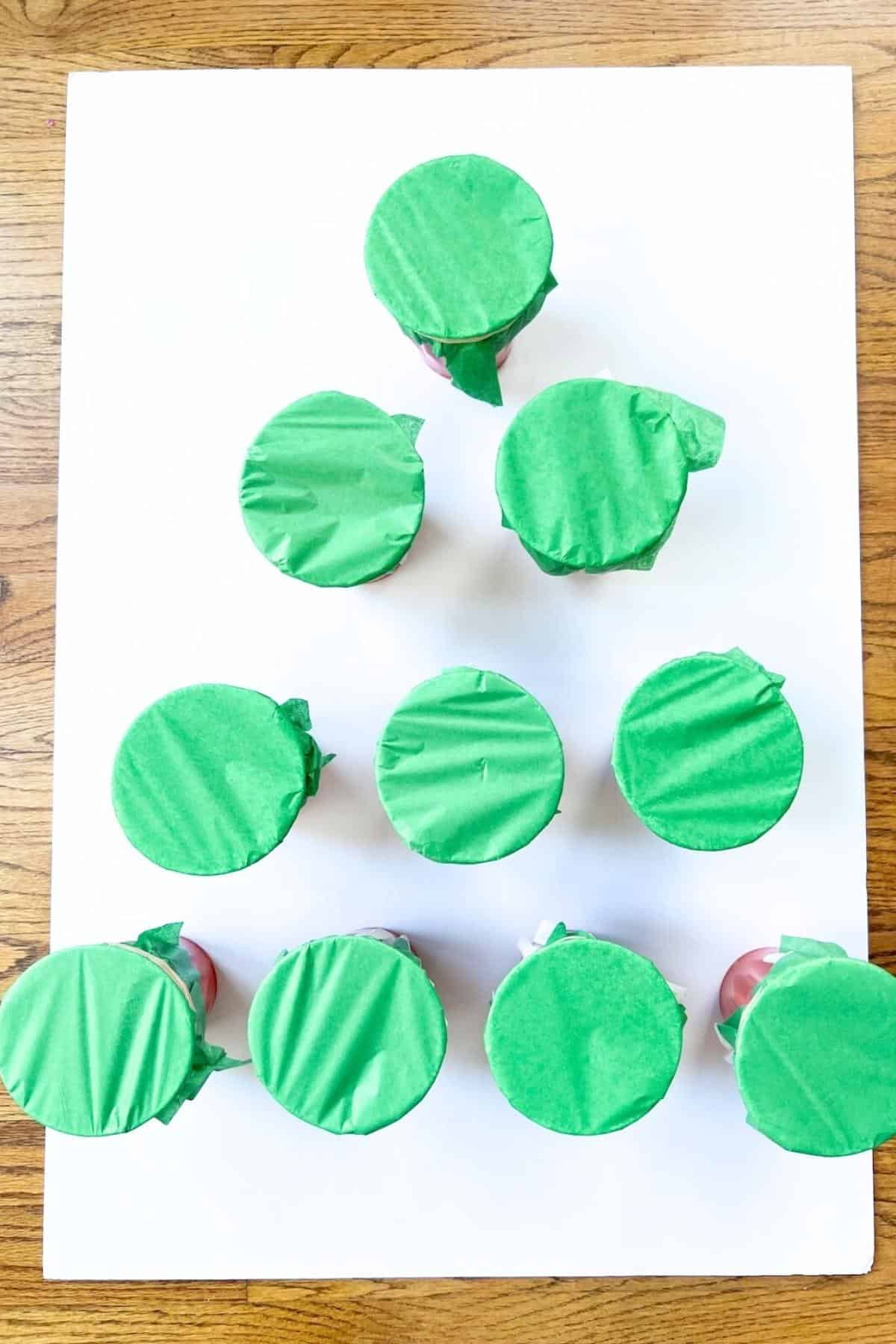 green tissue paper on cups glued to a white board.