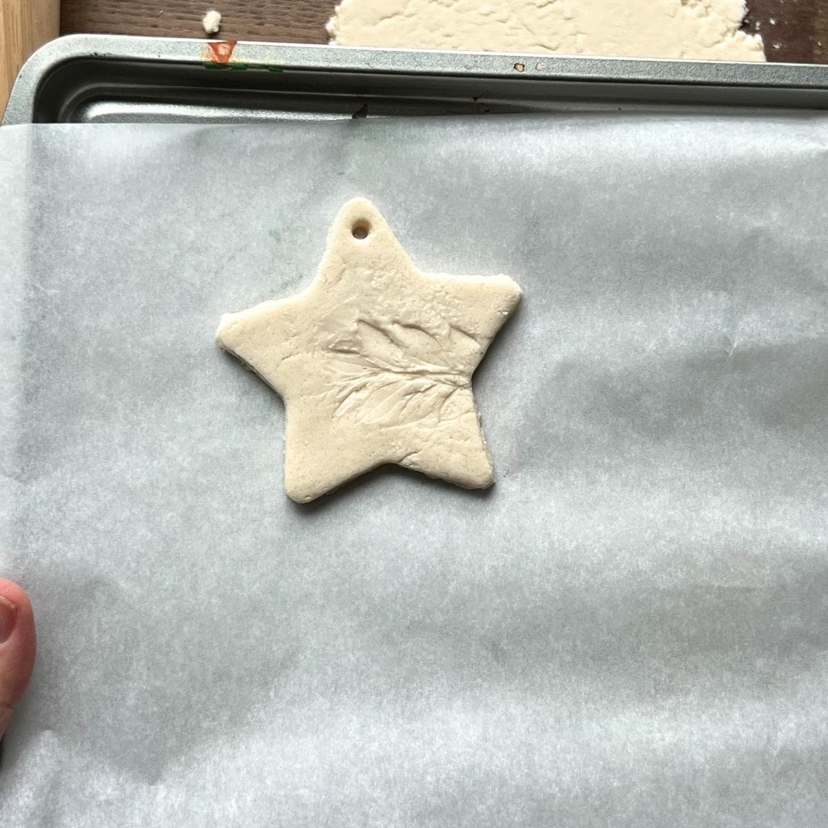 leaf impression salt dough star ornament on baking sheet.