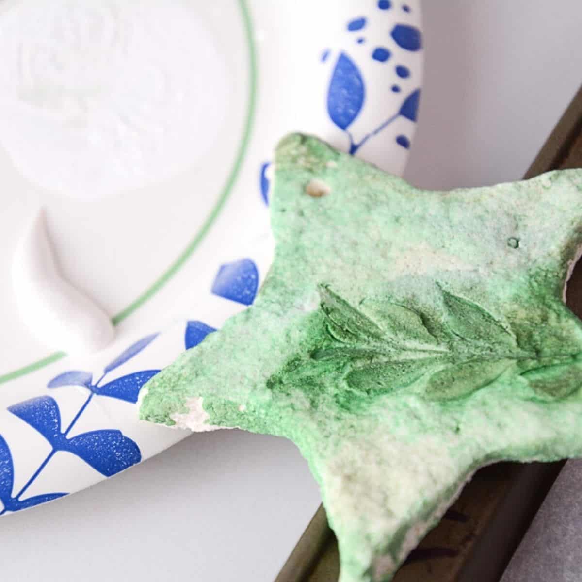 white glossy paint on plate with green leaf salt dough star resting on the plate.