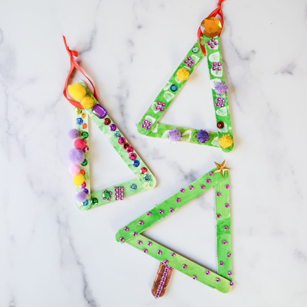 3 popsicle stick Christmas tree ornaments with decorations.