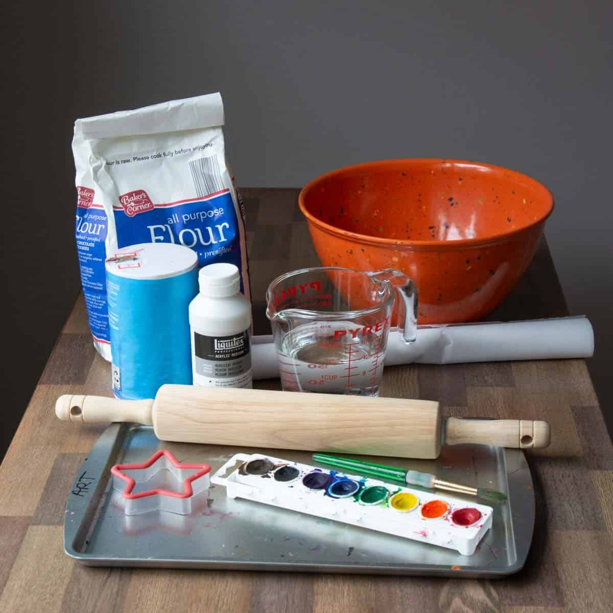 flour, salt, bowl, rolling pin, paints and water on a table.