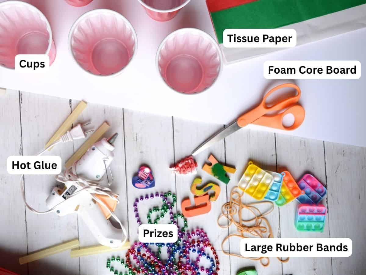 cups, prizes, scissors, foam core board and glue gun on a table.