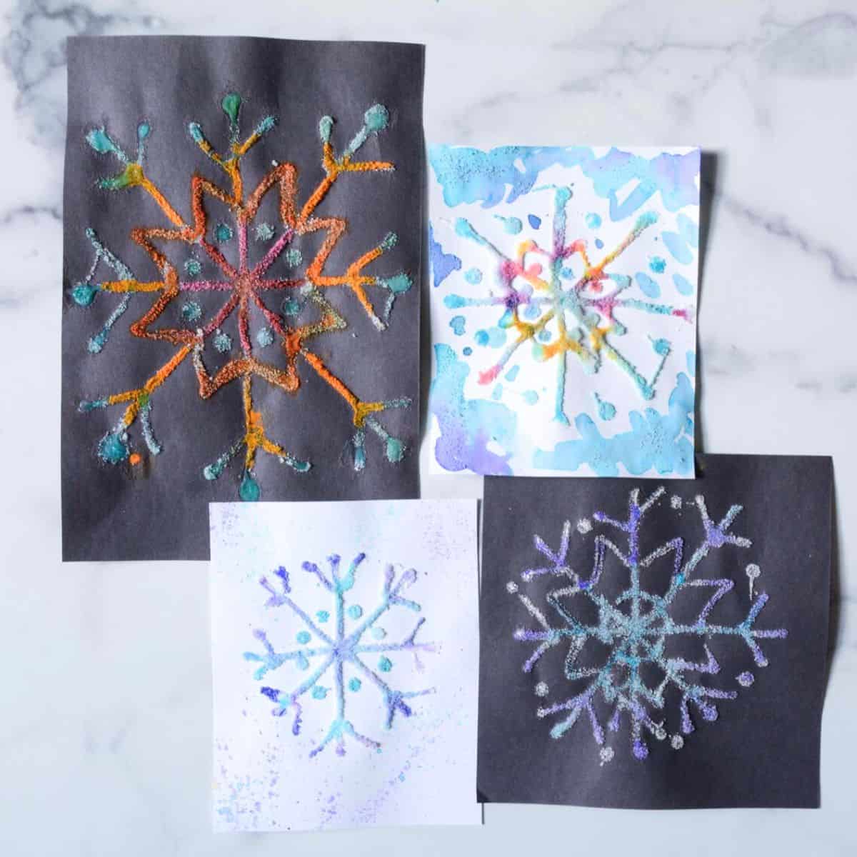 white paper and black paper raised salt snowflake designs.