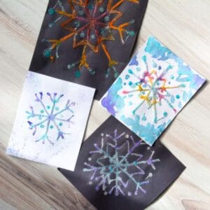 white paper and black paper raised salt snowflake designs.
