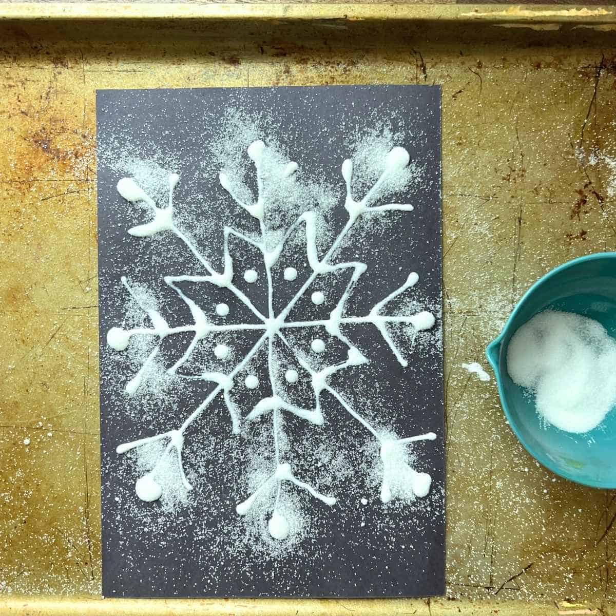 salt on glue drawn like snowflake on black paper.