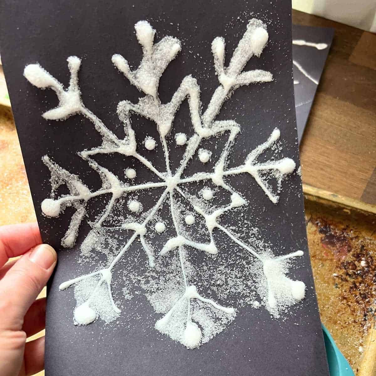 shaking salt off of snowflake glue drawing.