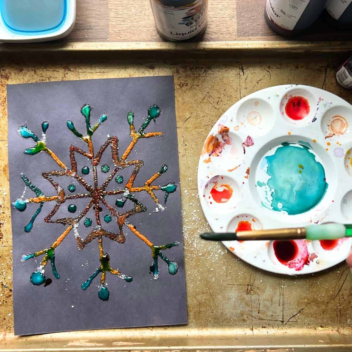 colorful raised salt snowflake painting on back paper.