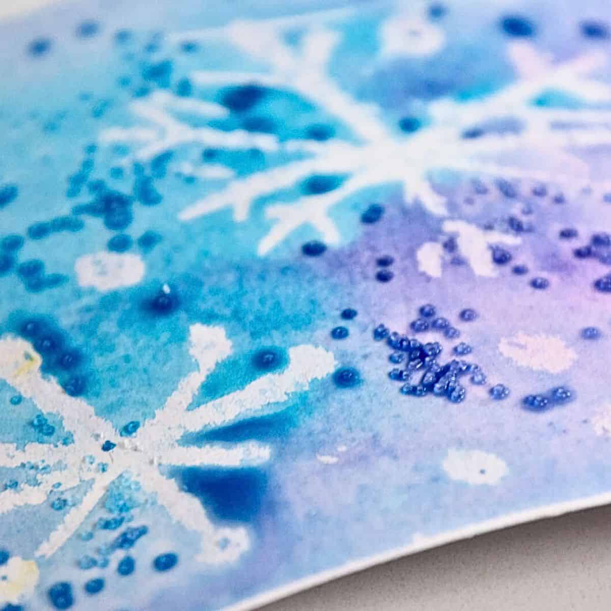 snowflake drawing with watercolor paint and salt around it.