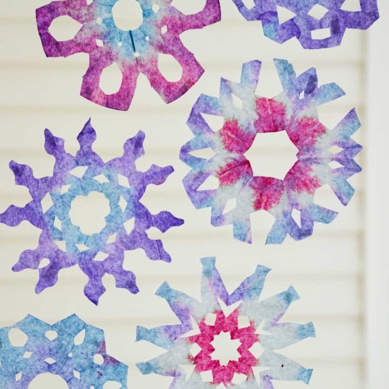 coffee filter snowflakes hanging on glass window.