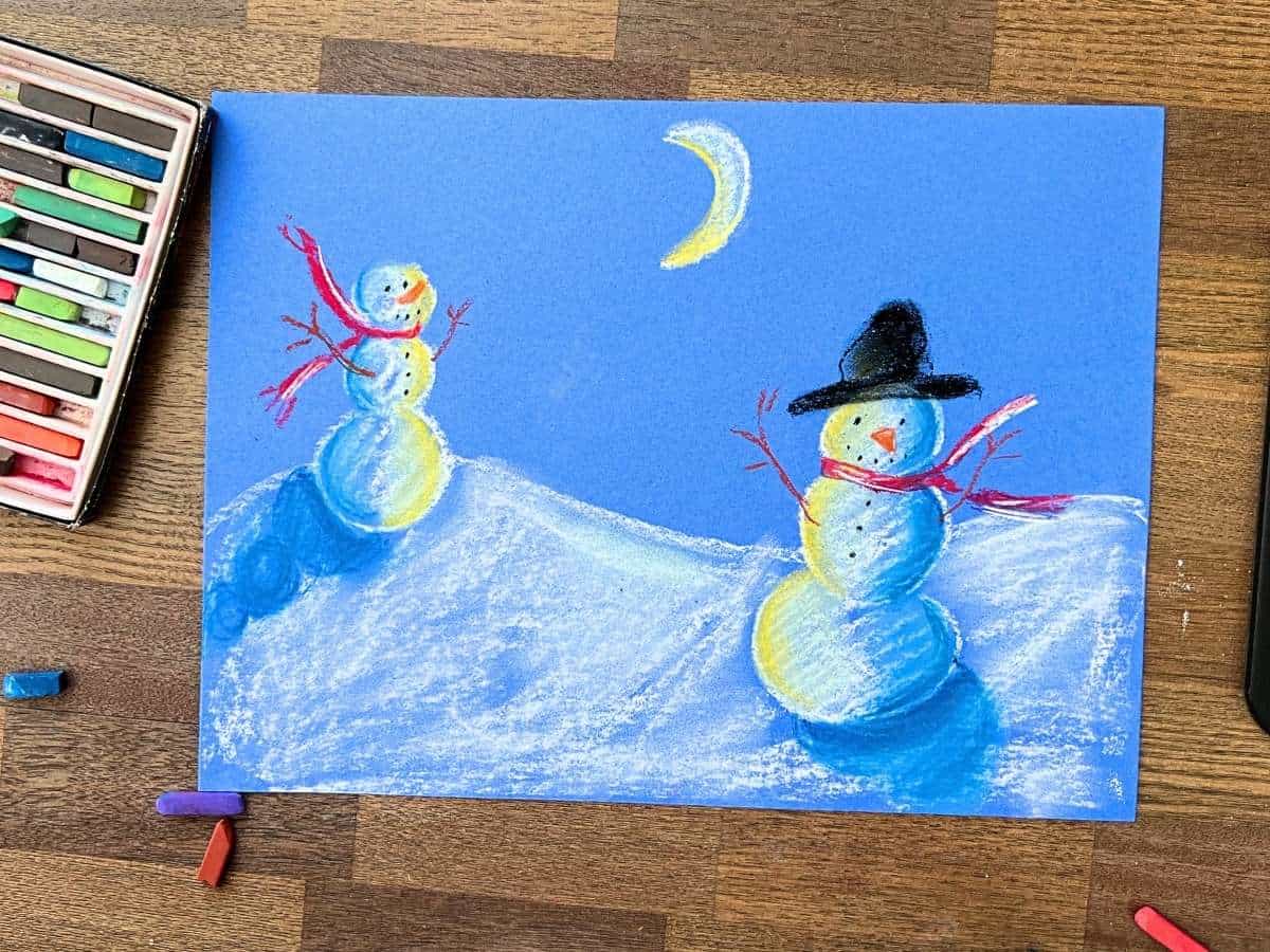 snowman at night chalk drawing on blue paper.