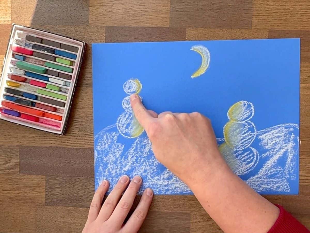 finger blending yellow chalk pastel with white chalk snowmen.