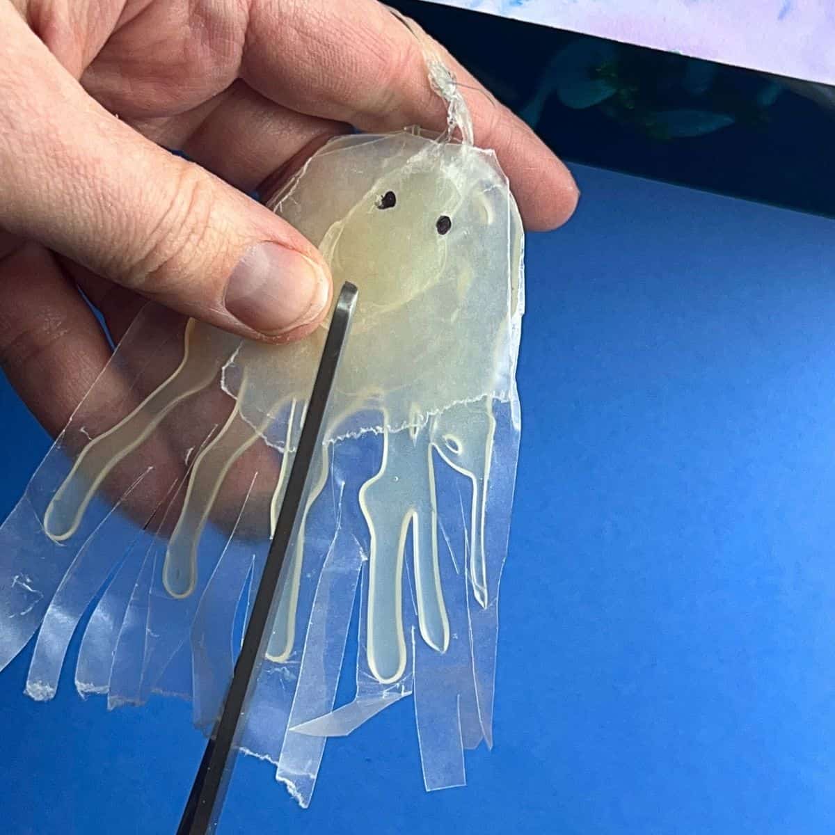 hand holding glue and wax paper jellyfish.