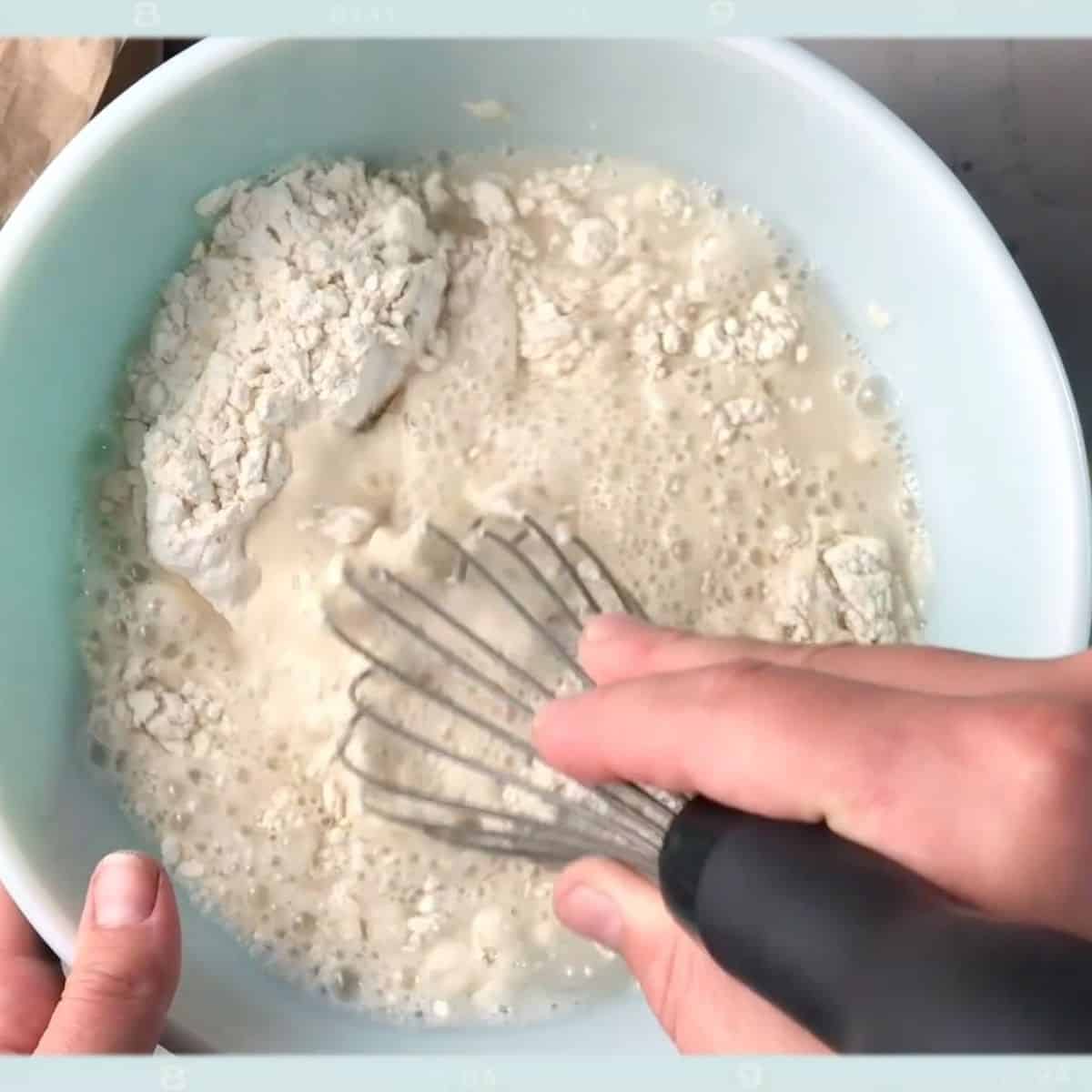 hand using whisk to make flour paper mache.