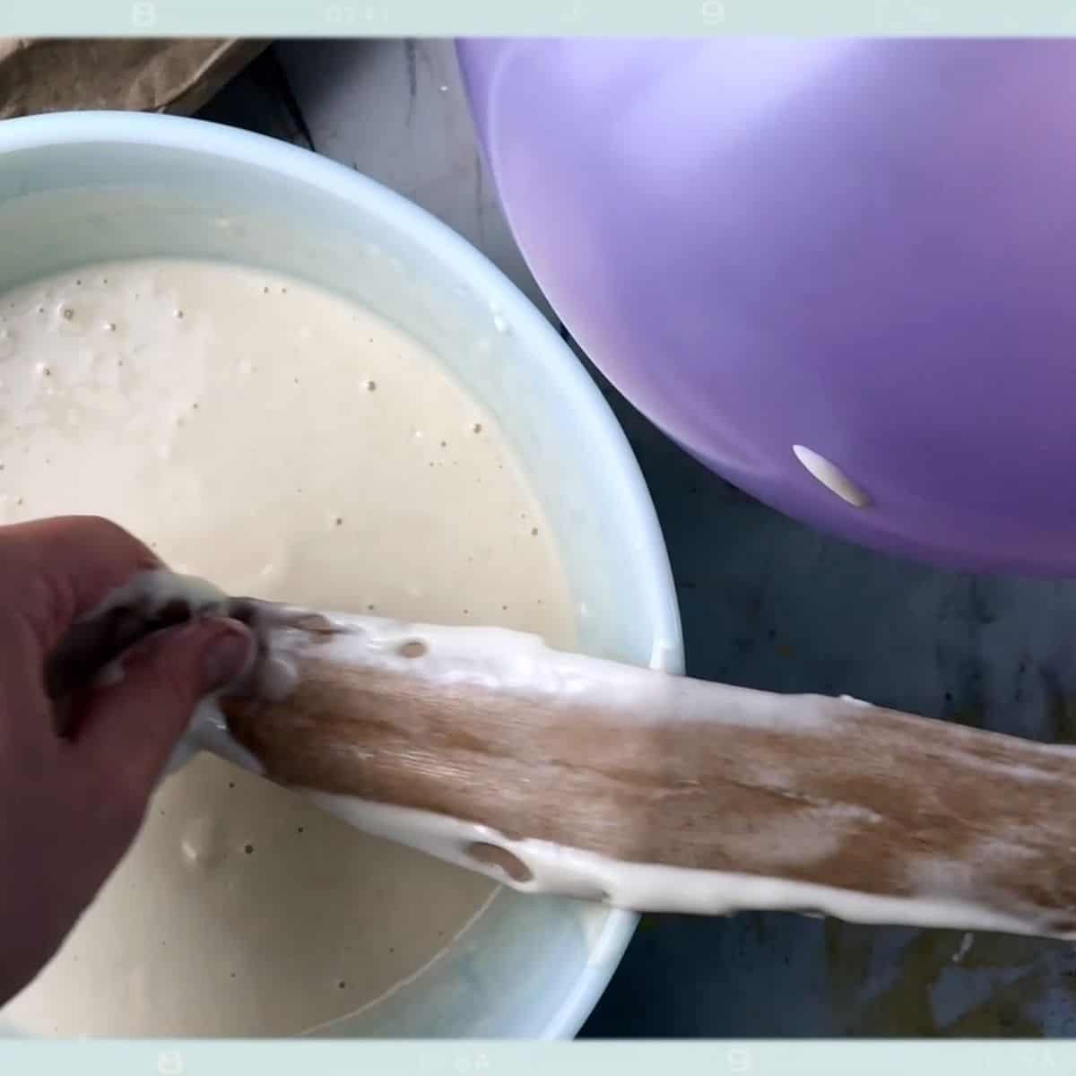 hands putting brown paper into flour paste.