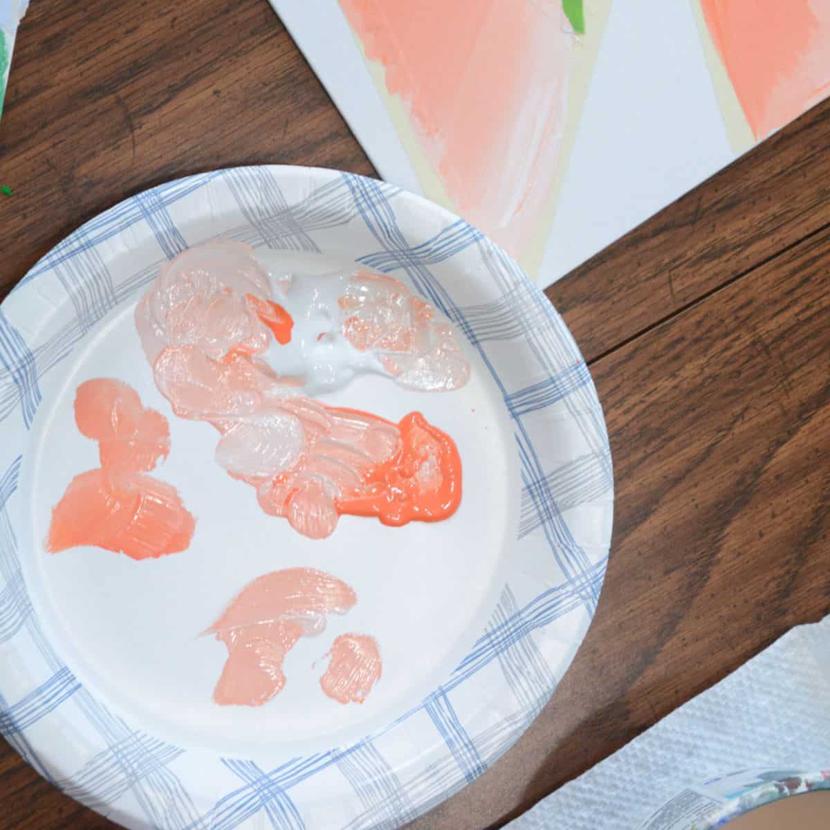 paper plate with orange and white paint mixed together.