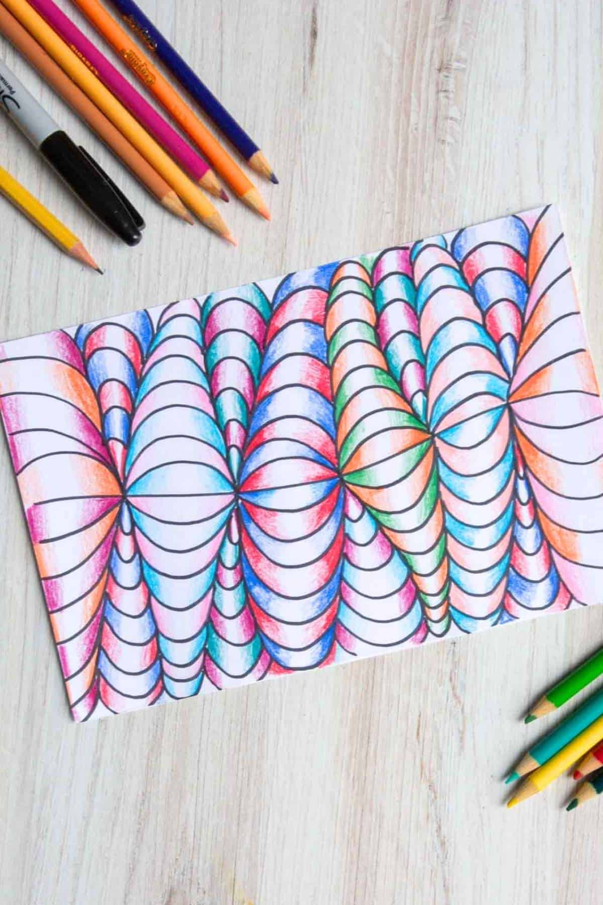 op art colored pencil drawing on a table with pencils and markers.