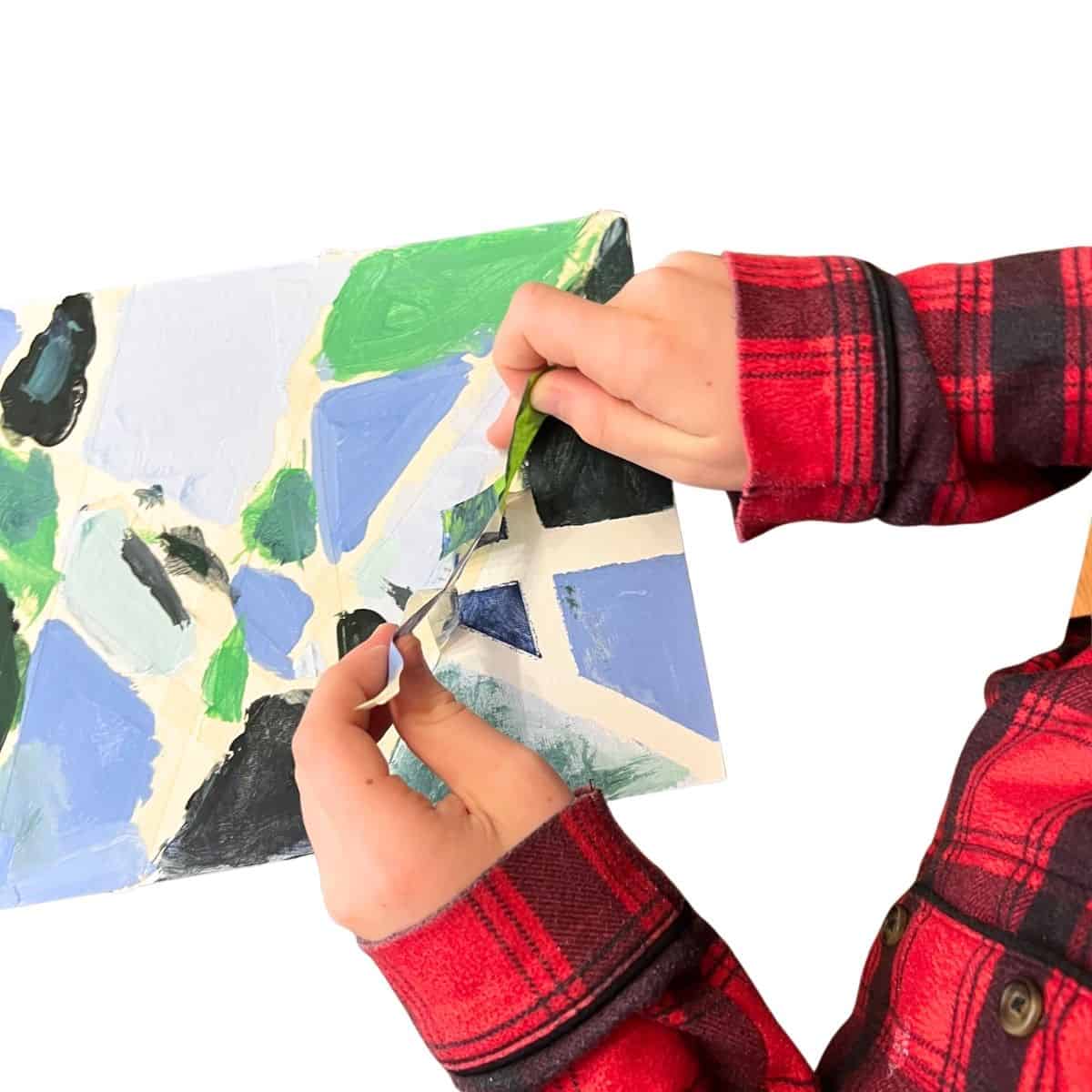 hand removing tape from canvas board.