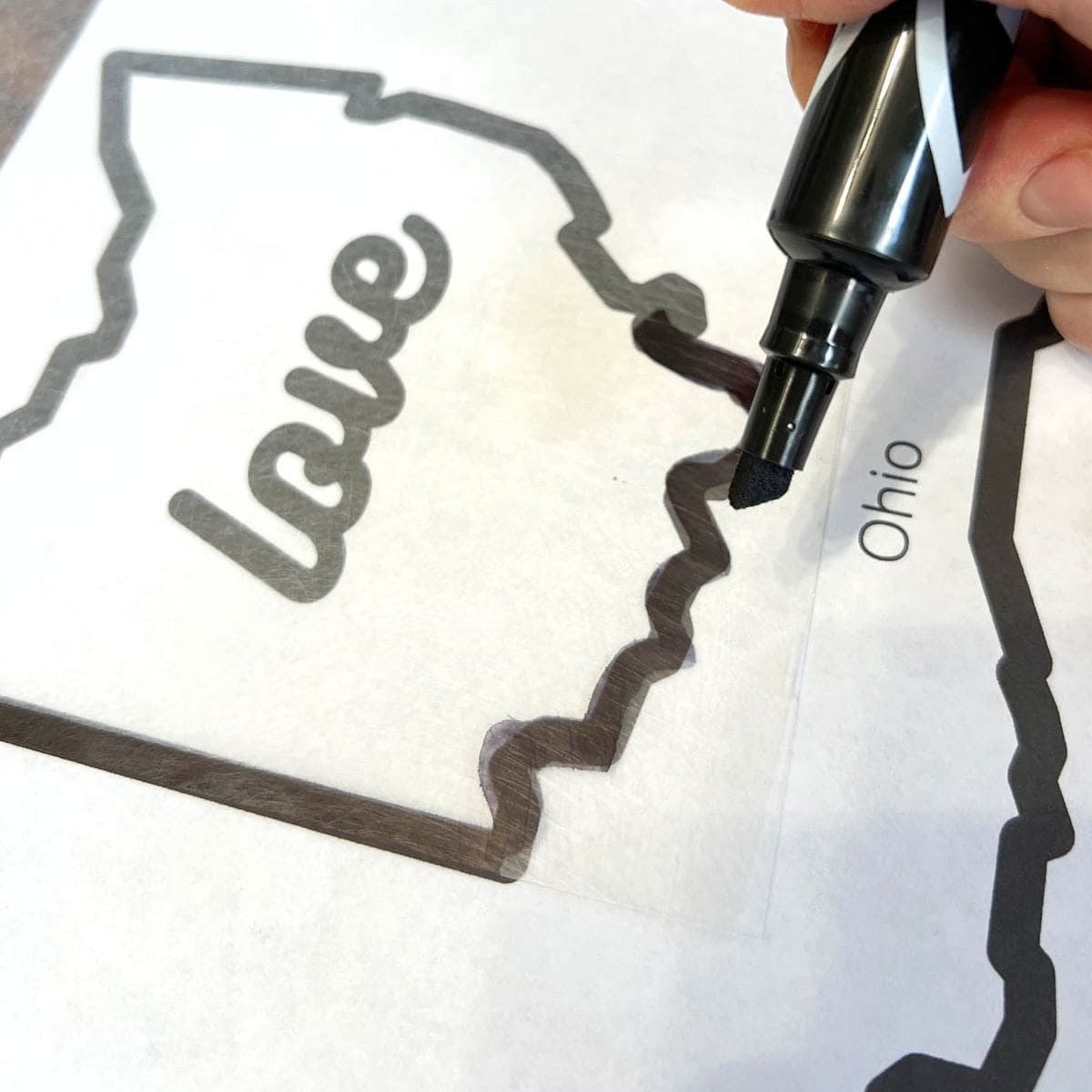 hand holding black marker tracing shape of Ohio.
