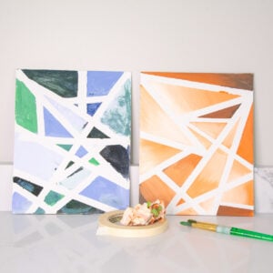 Abstract tape resist art on canvas showcasing tints and shades in green, blue, orange, and brown.