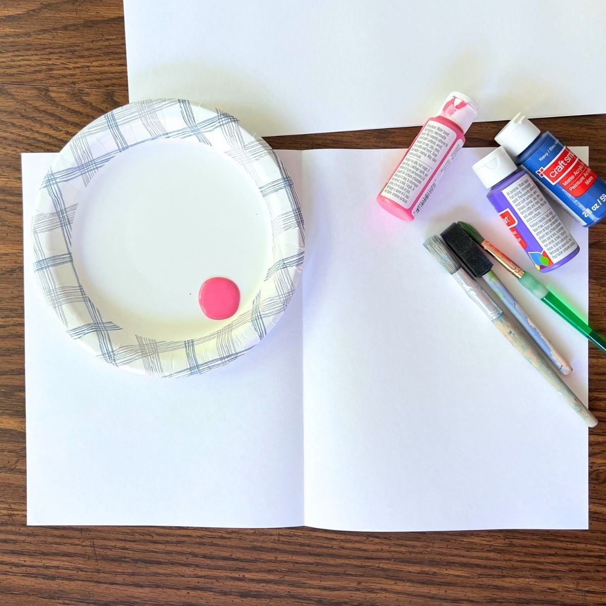 paint, white paper and paintbrush on a table.