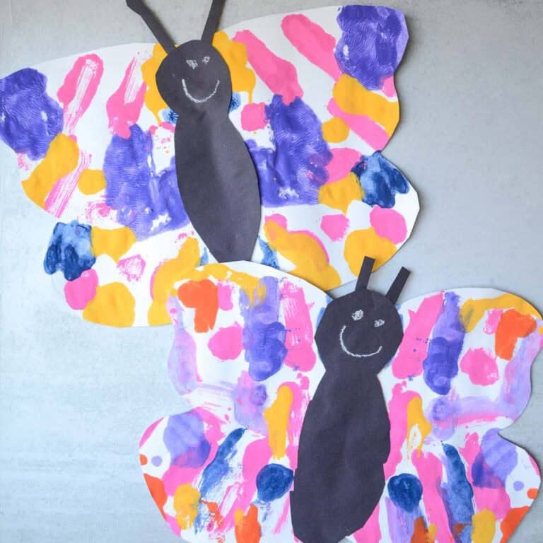 two painted paper butterfly crafts on a table.