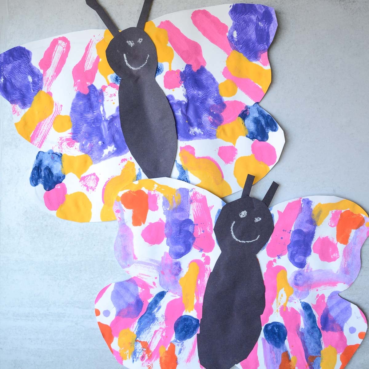 two painted paper butterfly crafts on a table.