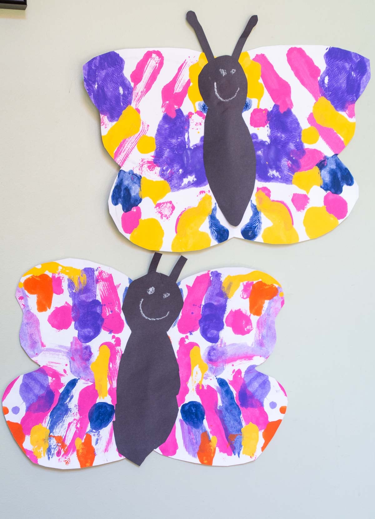 two painted paper butterfly crafts displayed on a wall.