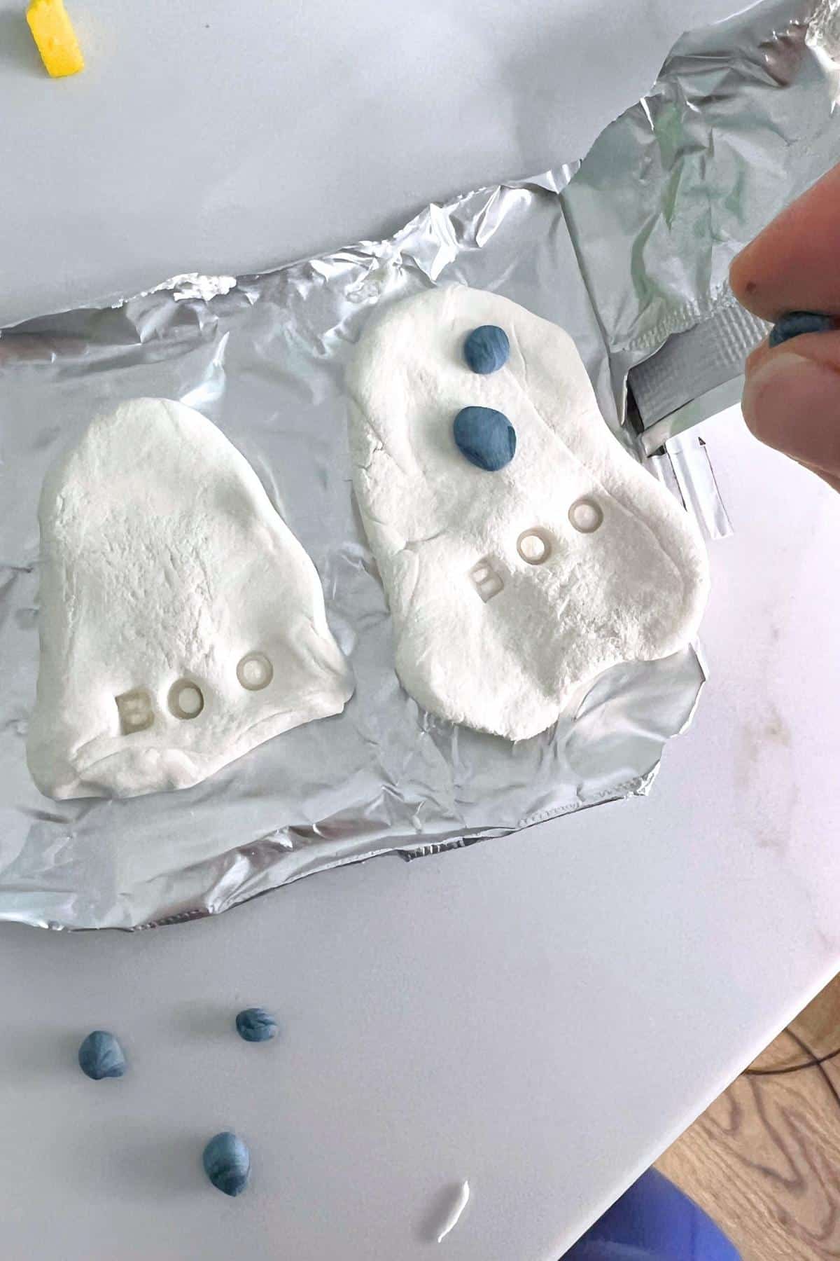 Child creating ghost figure using white Model Magic and black accents.