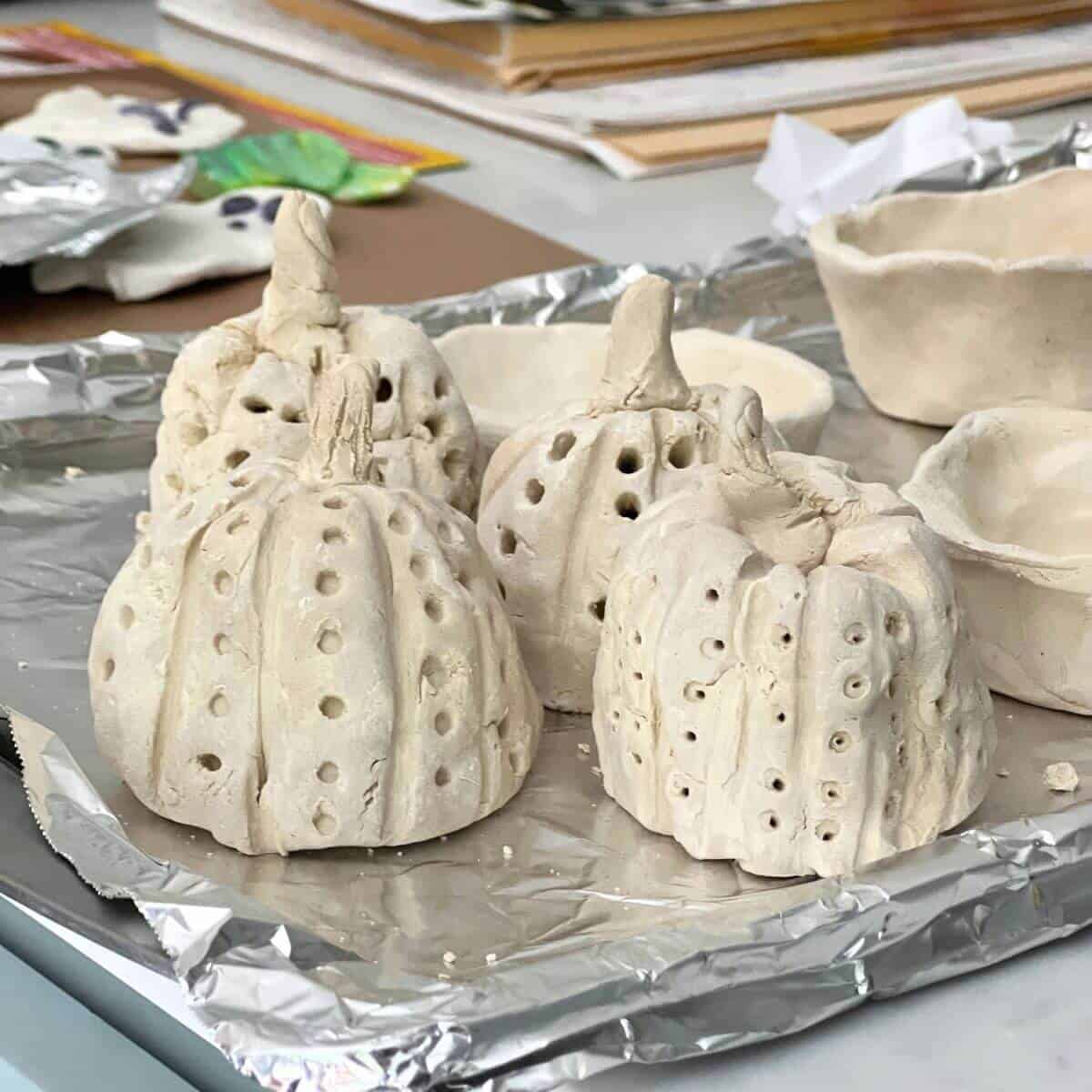 4 clay pumpkins sitting on a tray.