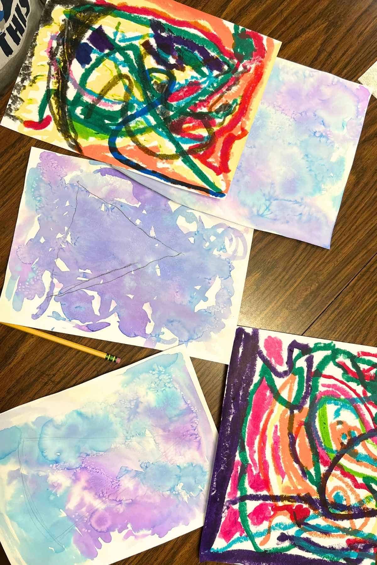 purple and blue watercolor papers and colorful scribbly papers on a table.