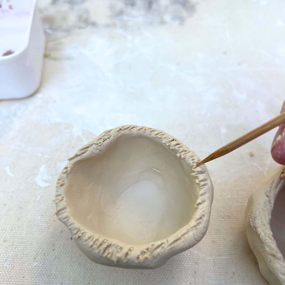 wooden skewer adding lines to pinch pot edge.