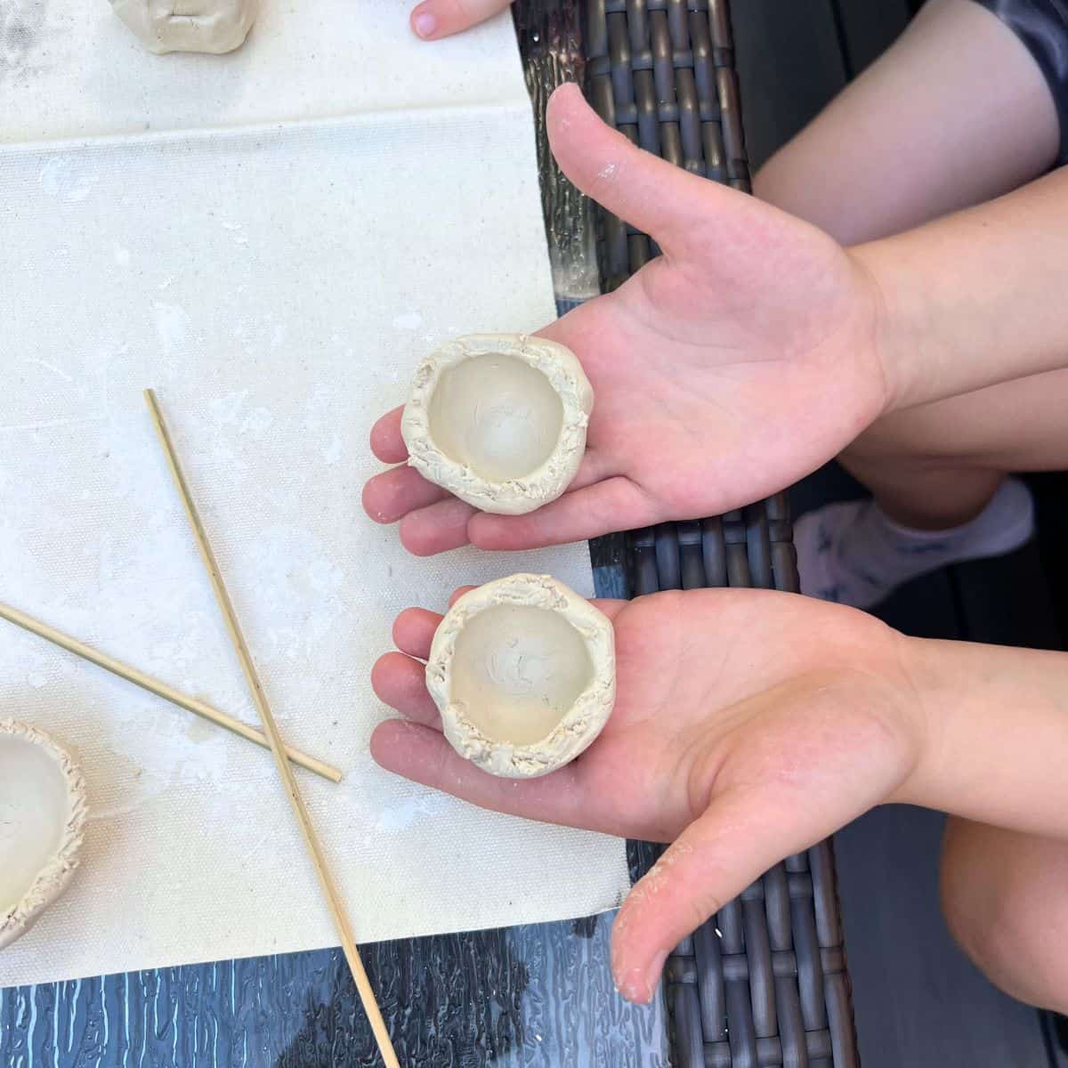 kids hand showing two pinch pots.