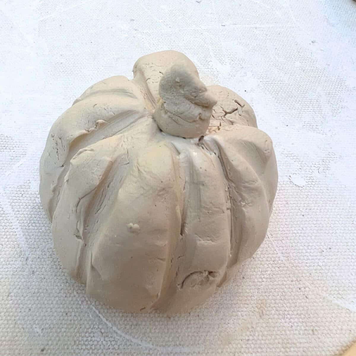 clay pumpkin with stem on a table.