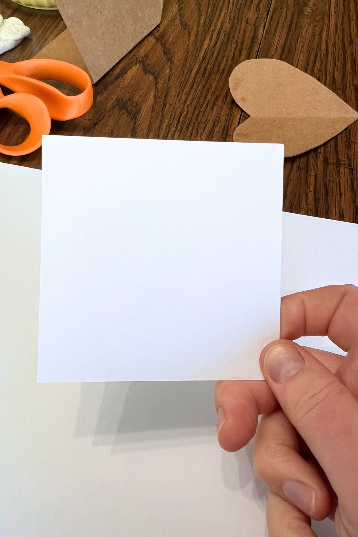 hand holding small piece square of white paper.