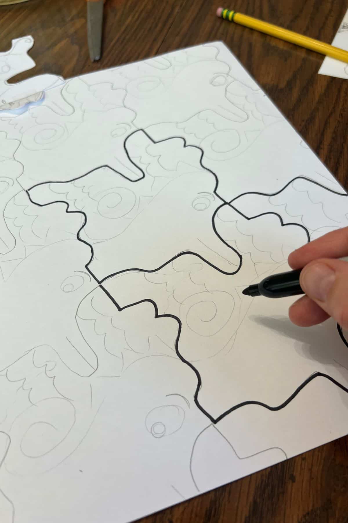 hand holding black marker to outline pencil lines.