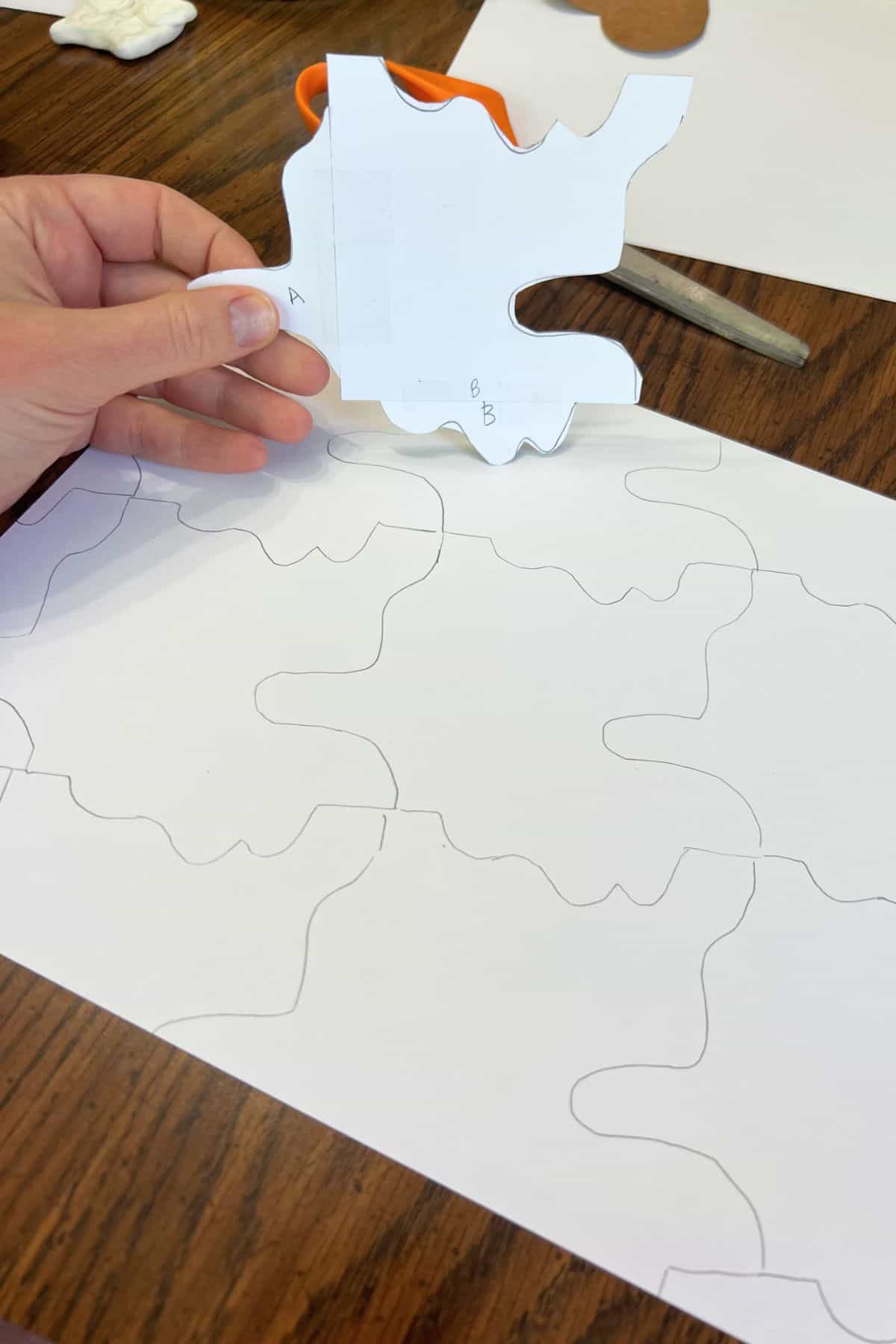 hand holding shape tracer and larger draw paper with lines on it.