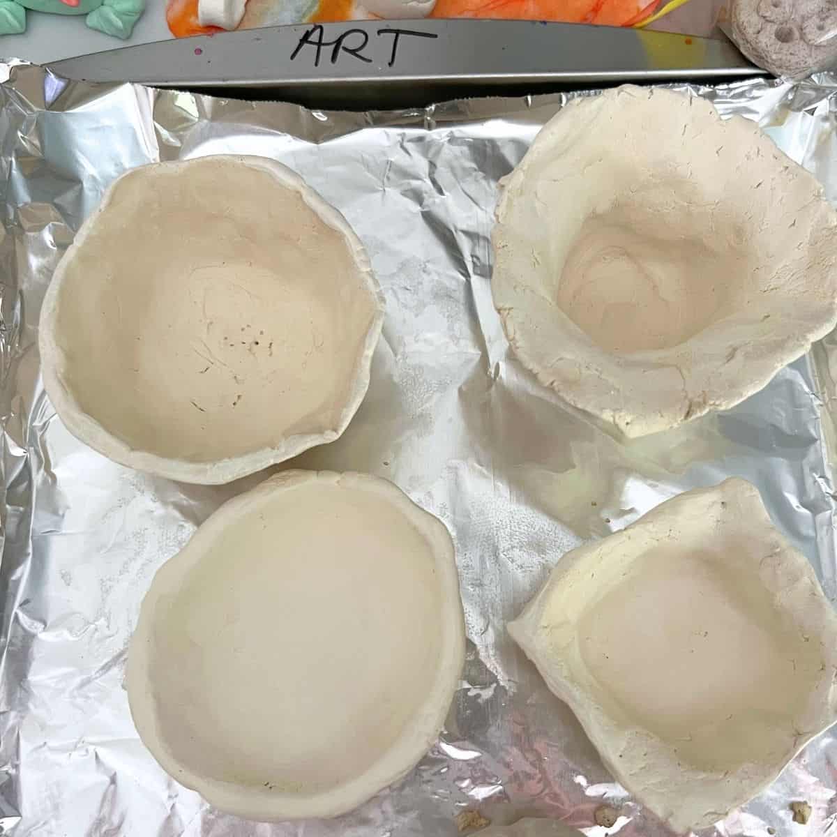pinch pot bowls on a baking sheet.