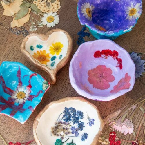 5 pressed flower clay dish art projects on a table.