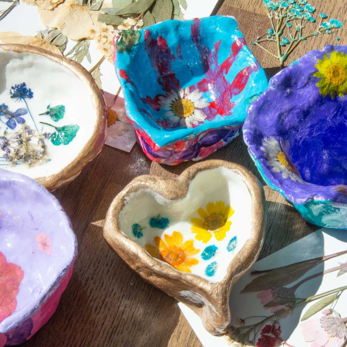 5 painted clay projects with pressed flower in them.